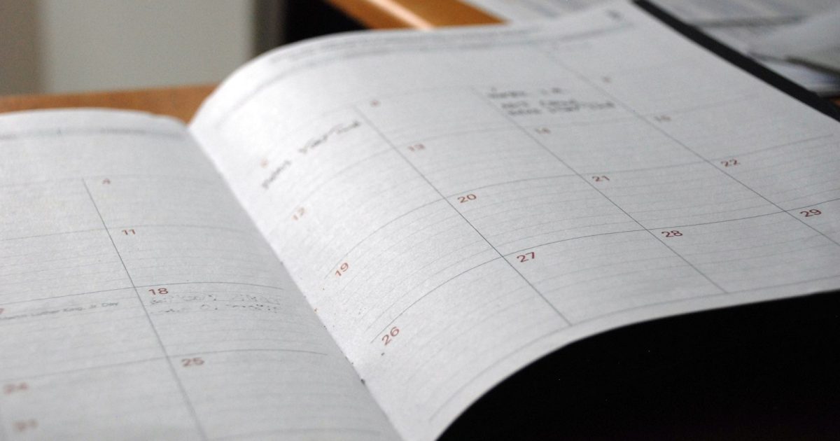 Agenda mensal aberta sobre uma mesa de madeira.