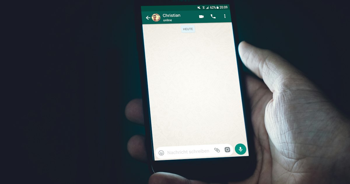 Mão segurando celular com conversa aberta no WhatsApp