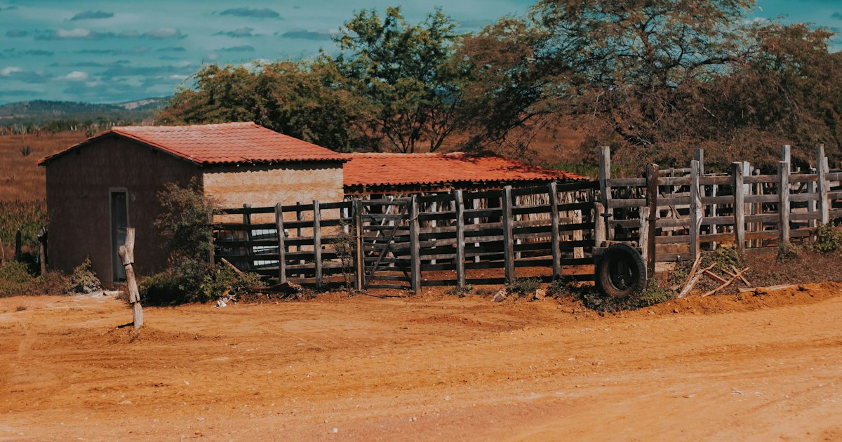 Estrada de terra vermelha e curral em área rural